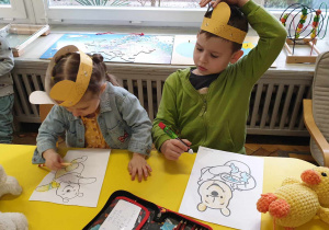 Na zdjęciu widzimy dzieci, które wykonują prace plastyczną "Kubusia Puchatka". Każde z dzieci na głowie ma opaskę z pszczółkami i uszami misia.