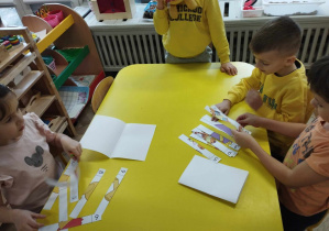 Na zdjęciu widzimy dzieci, które układają puzzle z ilustracjami przedstawiającymi Kubusia Puchatka i jego przyjaciół.