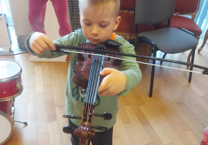 chłopiec próbuje grać na skrzypcach