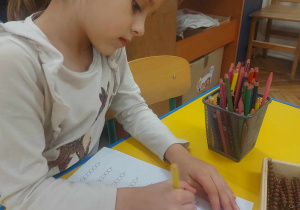 Dziewczynka, która pisze liczby i koloruje odpowiednią liczbę perełek