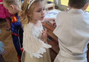 Zdjęcie przedstawia dziewczynkę przebraną za aniołka.