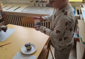 Zdjęcie przedstawia chłopca wysypującego sobie na dłoń posypkę do ciast.