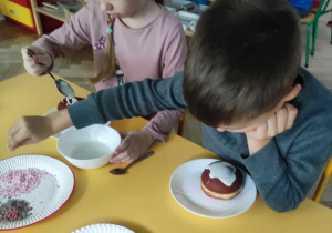 Dzieci dekorują posypką pączki