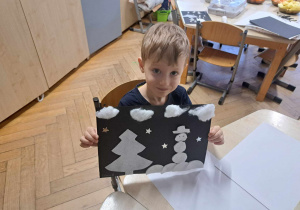 Zdjęcie przedstawia chłopca trzymającego swoją pracę.