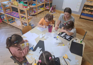 Zdjęcie przedstawia dzieci tworzące prace o zimie z użyciem różnych materiałów.
