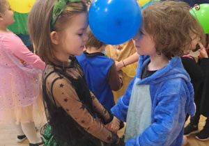 Zdjęcie przedstawia chłopca i dziewczynkę, trzymających między głowami balon.