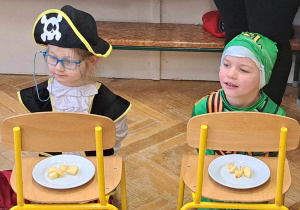Zdjęcie przedstawia dwóch chłopców siedzących przed talerzykami z jabłkami.