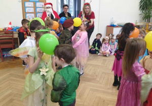 Na zdjęciu widzimy dzieci, które biorą udział w zabawie i trzymają między czołami zielony balon.