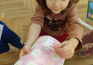 Zdjęcie przedstawia dziewczynkę, która pokazuje walentynkę.