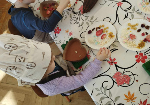 Na zdjęciu widzimy dziewczynkę, która tworzy własną dekorację na czekoladzie.