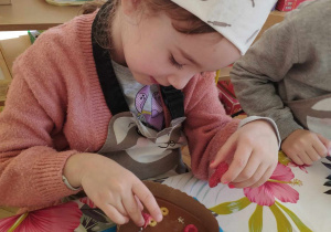 Na zdjęciu widzimy dziewczynkę, która tworzy własną dekorację na czekoladzie.