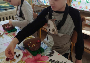 Na zdjęciu widzimy chłopca, który tworzy własną dekorację na czekoladzie.