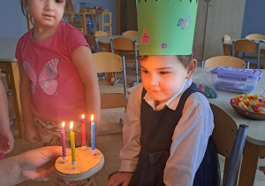 Zdjęcie przedstawia dziewczynkę przy torcie ze świeczkami.