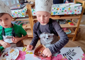 Dzieci siedzą przy stole i tworzą swoją własną czekoladę.