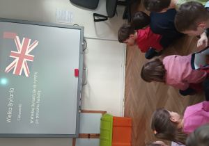 Dzieci siedzą i oglądają przygotowaną prezentację o Wielkiej Brytanii.