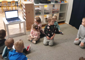 Zdjęcie przedstawia dzieci oglądające bajkę edukacyjną na laptopie.
