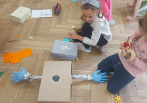 Na zdjęciu widać dzieci, które tworzą robota z dostępnego materiału