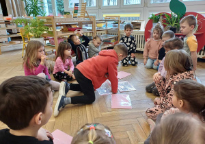 Dzieci siedzą na podłodze i grają w memory obrazkowe.