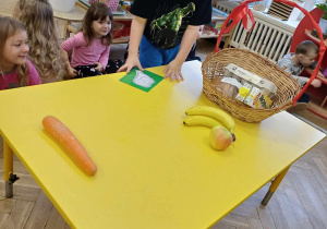 Dzieci siedzą dookoła stołu, na którym zgromadzone są różne produkty spożywcze..