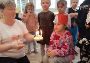 Dziewczynka zdmuchuje świeczki na symbolicznym torcie.