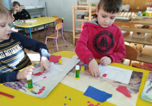 Na zdjęciu widzimy dwóch chłopców, którzy tworzą flagę Francji z wydartych kawałków papierów w odpowiednich kolorach.