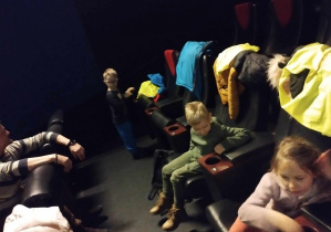 Na zdjęciu widzimy trójkę dzieci, które oczekują na film.