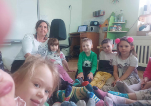 Dzieci z nauczycielem zebrane w kole na podłodze w kolorowych skarpetkach