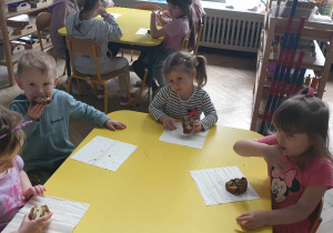 Zdjęcie przedstawia dzieci jedzące poczęstunek przyniesiony przez solenizanta.