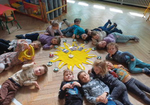 Dzieci leżące przy słoneczku urodzinowym.