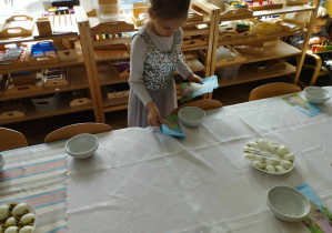 Na zdjęciu widzimy dziewczynkę, która rozkłada serwetki na stół wielkanocny.