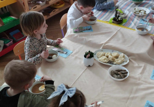 Na zdjęciu widzimy kilkoro dzieci, które jedzą wielkanocny obiad.