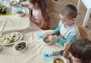 Na zdjęciu widzimy grupkę dzieci, które jedzą wielkanocny żurek z jajkiem.