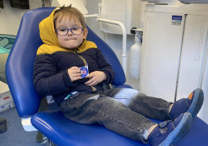 Zdjęcie przedstawia chłopca siedzącego na fotelu dentystycznym.