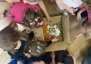 Zdjęcie przedstawia dzieci przy otwartym pudełku z jajkami czekoladowymi.