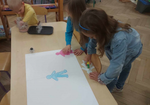 zdjęcie przedstawia dziewczynki tworzące plakat