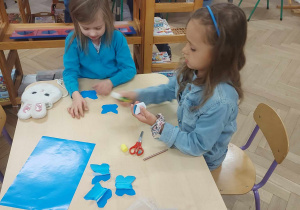 Na zdjęciu widać dzieci, które wycinają motyle z niebieskiego papieru