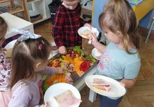 Zdjecie przedstawia dzieci trzymające talerze. Dzieci wybierają produkty,z których przygotują śniadanie.