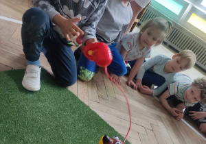 Dzieci bawią sią zabawką - pies robiący kupy