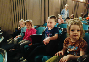 Dzieci siedzą na widowni w tatrze.