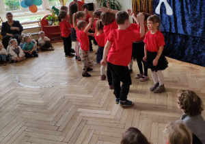 Zdjęcie przedstawia dzieci występujące podczas przeglądu - dzieci tańczą w parach.