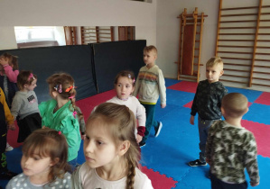 Na zdjęciu widzimy grupkę dzieci, która ogląda małą salę do ćwiczeń gimnastycznych i zabaw ruchowych.