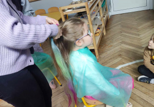 Uczennica wykonuje fryzurę dziecku