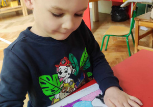 Chłopiec koloruje pastelami kolorowankę obrazującą dzieło Picassa