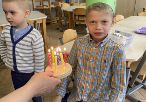Zdjęcie przedstawia chłopca przy torcie z zapalonymi świeczkami.