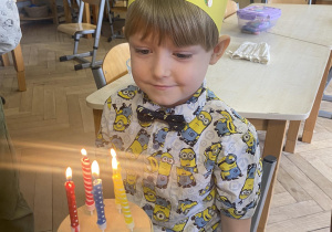 Zdjęcie przedstawia chłopca przy torcie z zapalonymi świeczkami.