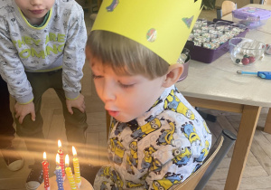 Zdjęcie przedstawia chłopca dmuchającego świeczki.