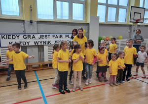Zdjęcie przedstawia grupę dzieci oraz osoby dorosłe na sali gimnastycznej. Dzieci oraz Panie pozują do zdjęcia.