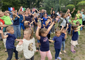 Zdjęcie przedstawia dzieci i rodziców biorących udział w zabawie muzyczno- ruchowej.