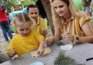 Zdjęcie przedstawia dziecko i rodzica wykonujących pracę z materiału naturalnego.