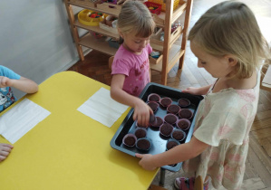 Na zdjęciu widzimy dziewczynkę, która częstuje babeczkami koleżankę.